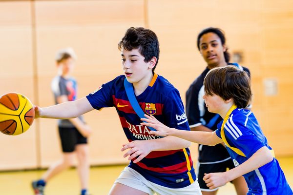 Schüler*innen, die beim Sportunterricht Basketball spielen