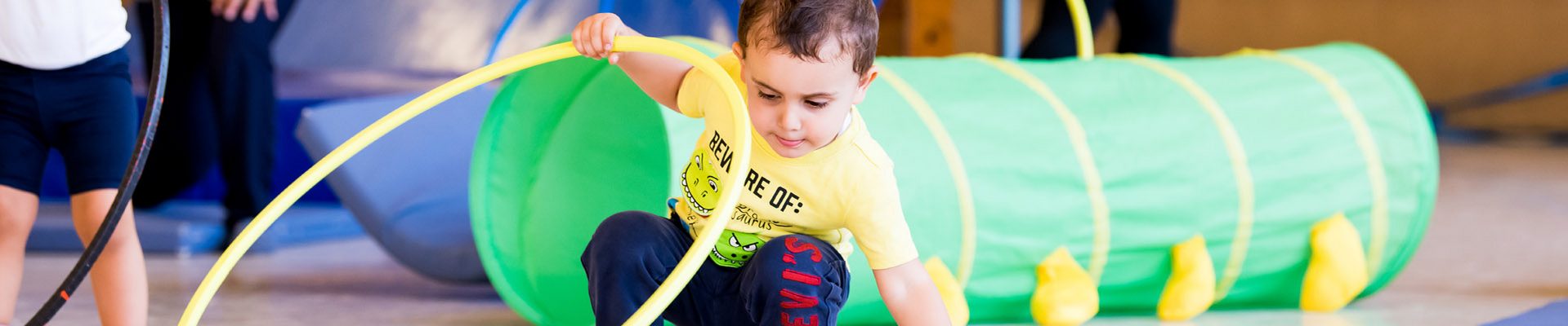 Teaser Kindertagespflege: Kind spielt mit Hula Hoop Reif