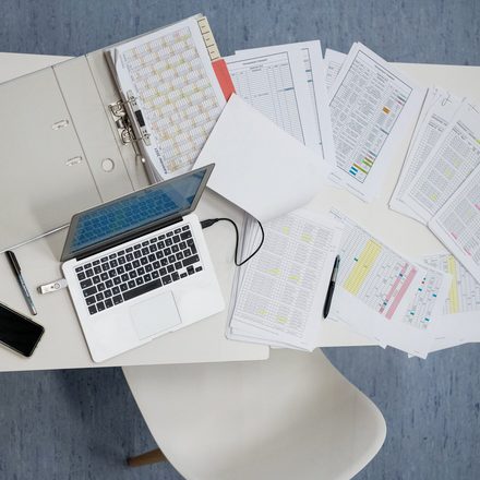 Ein Laptop steht auf einem Stapel aus Papier