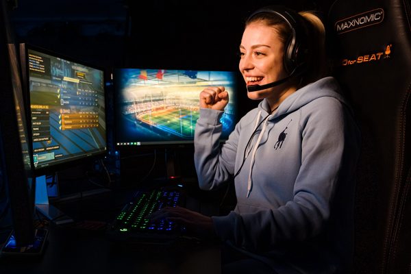 Frau, die vor Bildschirmen mit einem HeadSet sitzt 