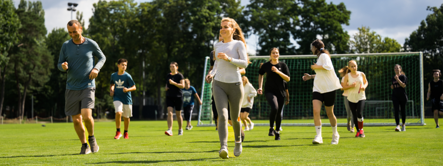 Symbolbild: Mehrere Jugendliche und Menschen machen Sport auf dem Rasen