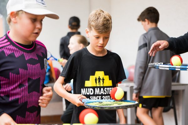 Kinder, die einen Ball auf eine, Tennisschläger balancieren 