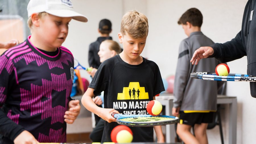 Kinder, die einen Ball auf eine, Tennisschläger balancieren 