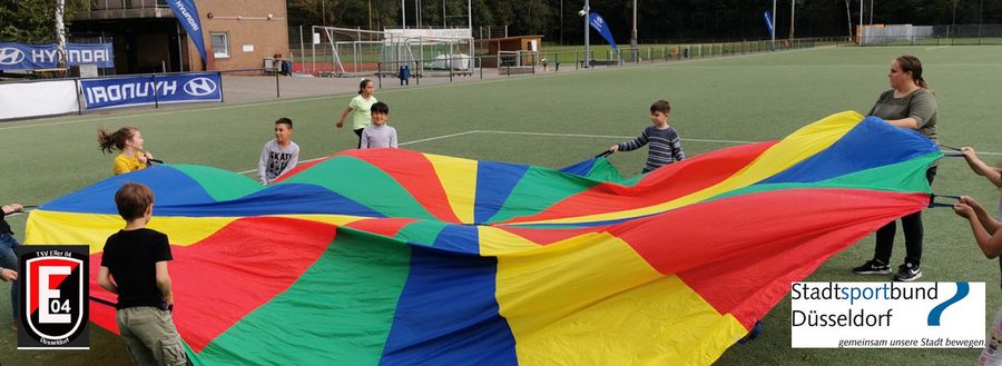 Kinder spielen mit dem Schwungtuch auf Sportplatz