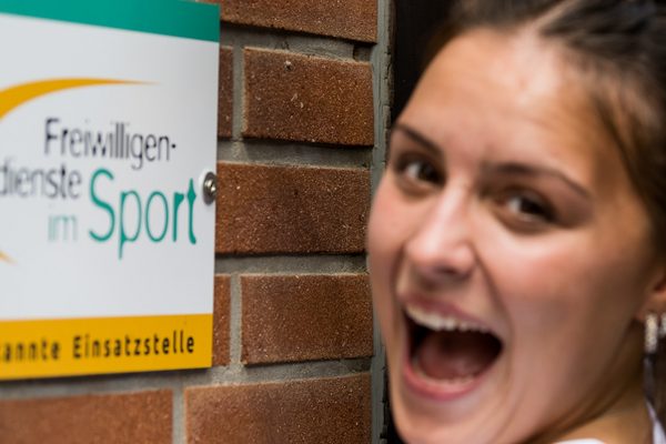 Mädchen zeigt auf Schild "Freiwilligendienste"